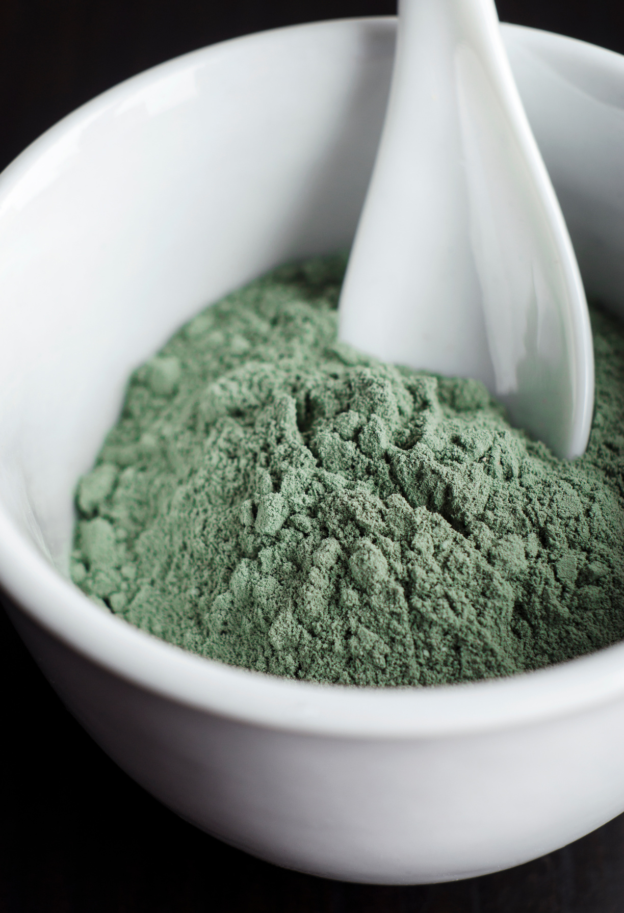 Green cosmetic clay powder in a bowl